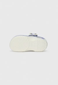 Bela podloga otroškega superge z modrim obrobo in črnim ter modrim sponko na enobarvni svetlo sivi ozadju.