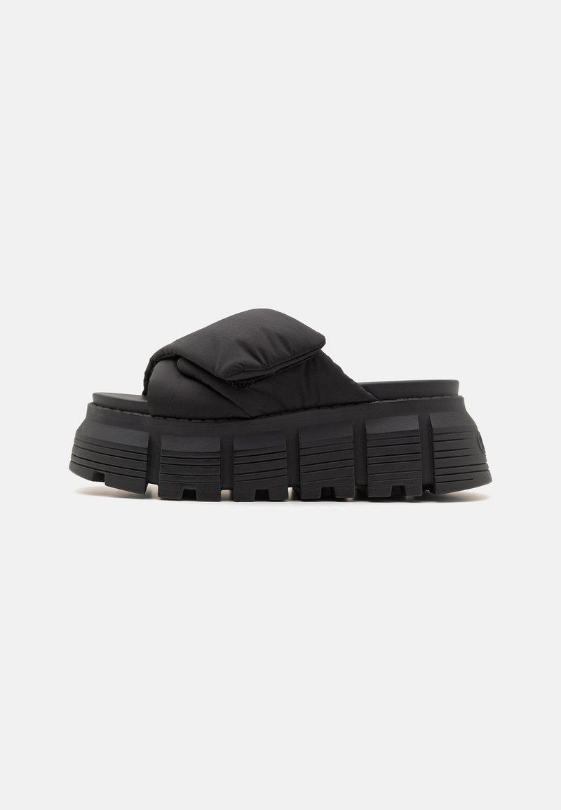 Chausson noir avec une tige rembourrée et une semelle en caoutchouc épaisse et rainurée. Il présente un design minimaliste et une forme arrondie pour un soutien du pied.