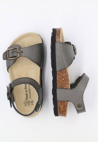 Sandale en cuir gris avec boucle sur le côté, semelle en liège, semelle texturée et design à talon ouvert. Légère, avec une surface lisse et des accents minimaux.