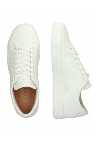 Baskets en cuir blanc avec une texture lisse, bout rond et semelle en caoutchouc plate. Présentent un design minimaliste et un système de laçage.