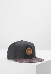 Szürke farmer snapback sapka elöl egy kerek logópatccsal, színes mintázatú karimával, amely bonyolult mintákkal díszített.