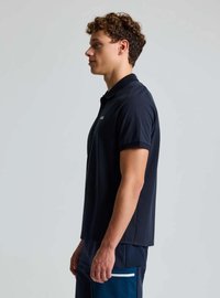 Marineblaues Poloshirt mit klassischem Kragen und kurzen Ärmeln, mit einem dezenten Logo-Detail auf der linken Brust. Glatte Stoffstruktur.