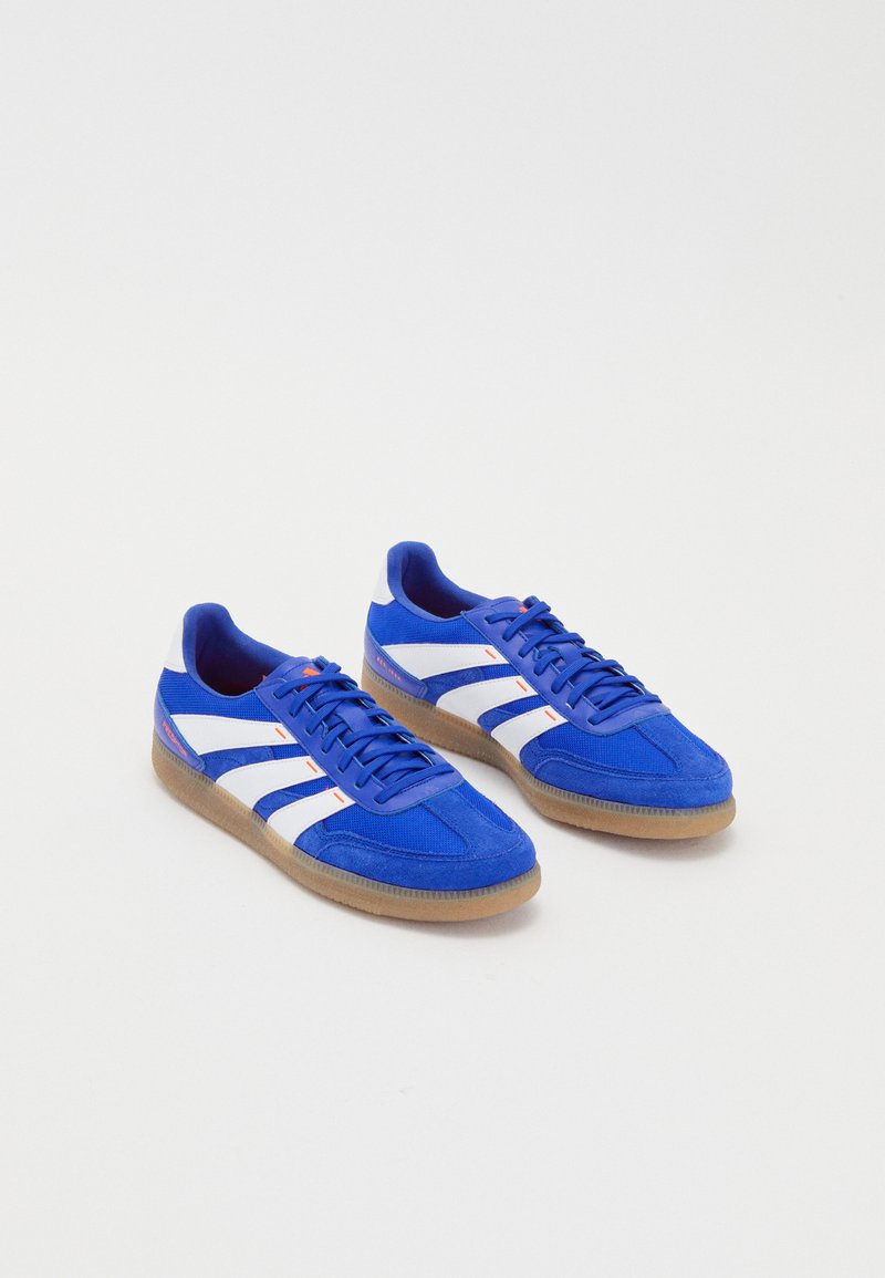 Blue athletic shoes with white stripes and gum sole. Features a mesh and suede upper, rounded toe, and flat laces.