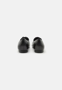 Black leather shoes with a smooth finish and rounded toe, featuring a low heel and no visible hardware, viewed from the back.