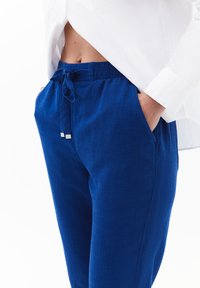 Blauwe linnen broek met een elastische tailleband en trekkoord, voorzien van zijzakken en een gladde textuur. Pasvorm met een aansluitende snit.
