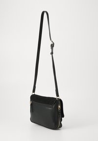 Borsa a tracolla in pelle nera con pattina in suede, dettagli in zip dorati, tracolla regolabile e finitura liscia. Forma rettangolare compatta.