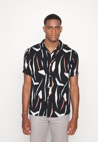 Chemise à manches courtes avec boutons, de couleur noire, ornée de motifs abstraits blancs, orange et beiges. Tissu léger, coupe décontractée et col.