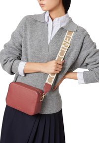 Borsa a tracolla rossa in pelle con forma rettangolare, dotata di una tracolla regolabile con motivo e hardware in tonalità oro. Finitura texture.