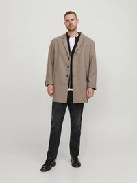 Παλτό μπεζ σε μείγμα μαλλιού με εξαιρετικά φαρδιά γραμμή, τρία κουμπιά και γιακά με εγκοπές, συνοδευόμενο από σκούρο τζιν και μαύρα μποτάκια με κορδόνια.