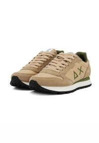 Sneaker beige con upper in suede e mesh, dettagli verdi e logo. Texture morbida, punta rotonda, soletta bianca e suola in gomma nera.