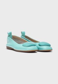 Bailarinas de cuero turquesa con punta redondeada, acento acolchado prominente y tirador en el talón. Exterior suave y suela flexible.