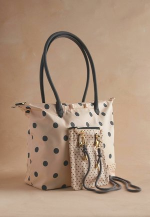 Borsa a tracolla a pois rosa chiaro con manici neri. Presenta una pochette a pois più piccola attaccata con accessori in oro e lacci grigi.