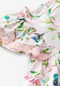 Rochie cu imprimeu floral, cu dantelă roz la margine, decorată cu imprimeuri cu colibri și flori pe un material delicat și ușor. Mâneci volănașe pentru un plus de textură.