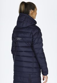 Navy blue puffer jacket with a hood, featuring horizontal quilted sections and a logo on the upper back. Smooth texture and lightweight design.