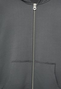 Sivé mikina na zips s centrálnym strieborným zipsom a dvoma prednými vreckami s viditeľnými švy.