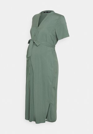Vestido de maternidade verde, até os joelhos, com mangas curtas, botões na parte da frente e um cinto amarrado na cintura; apresenta fendas laterais para maior conforto.