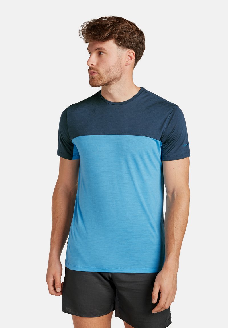 Herrkortärmad idrottströja; har en blå underdel och en mörkblå ovandel; rund halsringning, slät textur.