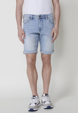 Lichtblauwe denimshorts met omgeslagen manchetten, vijf-pocketontwerp en een subtiele vervaging. Gecombineerd met wit en grijs sneakers.