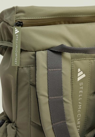 Olive green backpack with a textured surface, featuring a roll-top closure, adjustable straps, and a branded tag with "Stella McCartney."