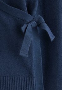 Marineblå strikket cardigan med bindebånd foran, ribbet struktur i kanten og blødt stof.