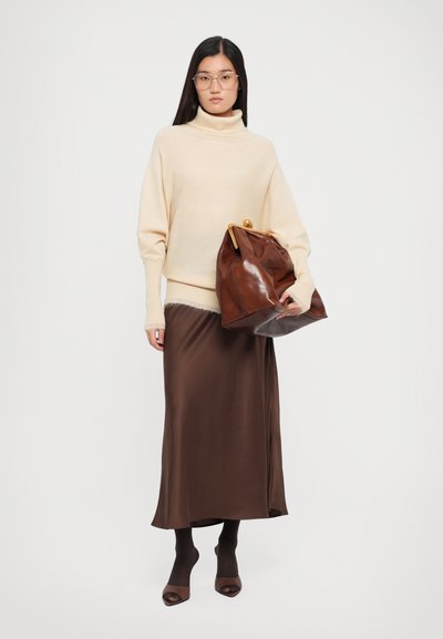 Beige korkeapaitainen neule, ruskea satiinihame, ruskea nahkakassi kultaisilla yksityiskohdilla sekä ruskeat sukkahousut avokkaiden kanssa.