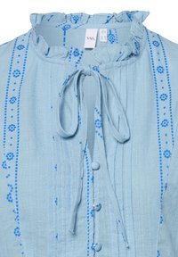 Lichtblauwe blouse met een gerimpelde kraag, gestrikt halslijn en blauwe bloemenborduursels. Beschikt over verticale streepdessins en knoopsluitingen.