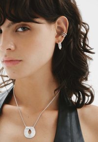 Conjunto de joyería de plata que incluye un colgante en forma de lágrima texturizada en una cadena y un arete de gancho multi banda con pendientes en forma de aro.