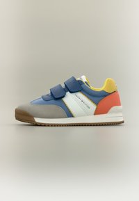 Μπλε και γκρι αθλητικό παπούτσι με λουράκια με βέλκρο, λευκές λεπτομέρειες και πολύχρωμη φτέρνα. Η καουτσούκ σόλα και το σουέντ υλικό δημιουργούν ένα υφασμένο φινίρισμα.