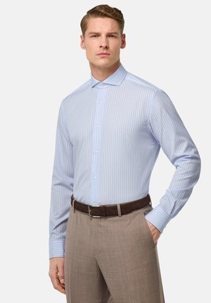 Camicia a righe azzurre e bianche con colletto a punta, chiusura con bottoni, maniche lunghe e una texture liscia, abbinata a pantaloni beige e una cintura marrone.