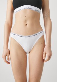 Perizoma bianco in cotone con cintura logo Calvin Klein. Presenta una texture liscia e un design semplice, che enfatizza una silhouette aderente.