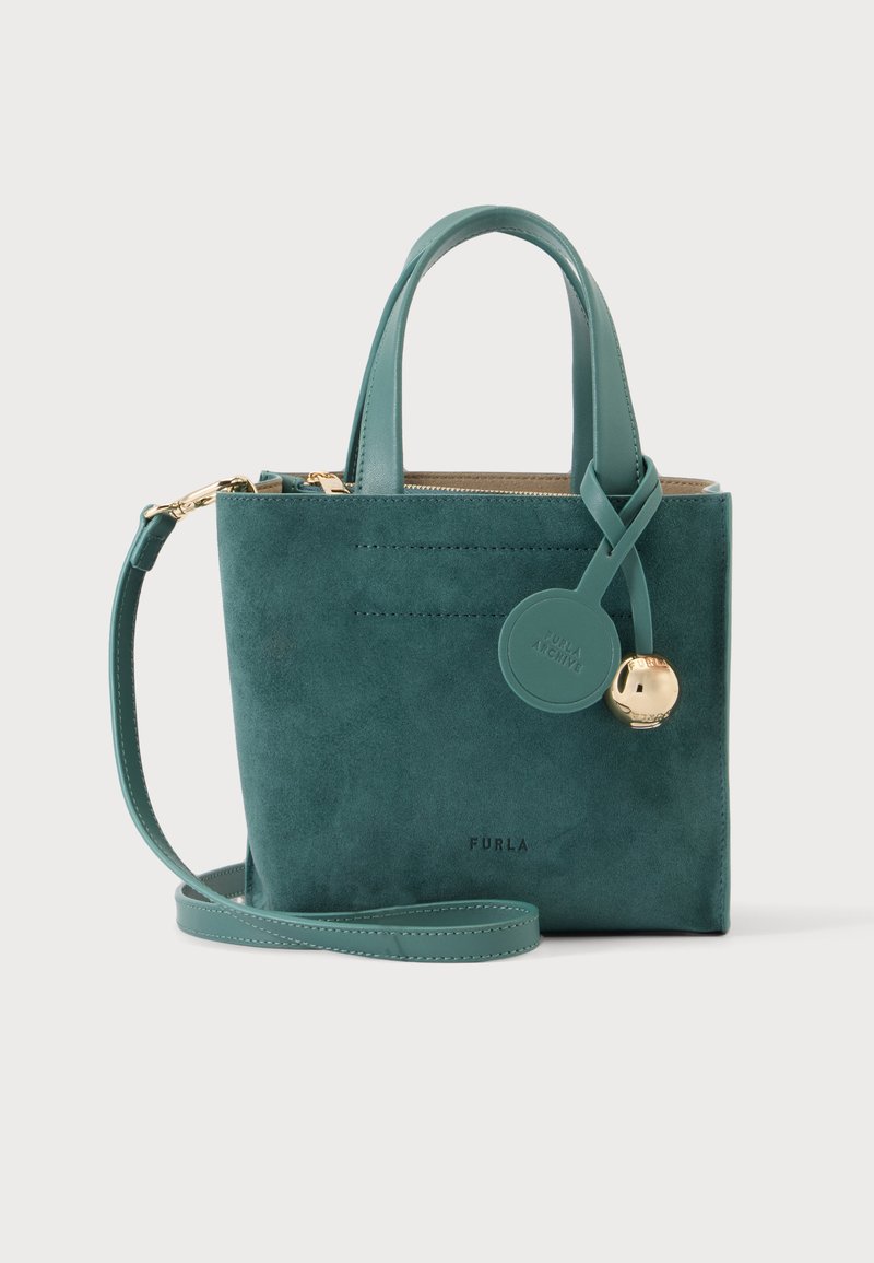 Petit sac à main en daim bleu sarcelle avec poignées supérieures, une bandoulière amovible et une étiquette ronde avec un charm en or sur le devant.