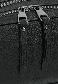 Borsa a spalla in pelle nera con texture, dotata di cerniere e tiranti in metallo argentato. Presenta un logo impresso e dettagli in pelle liscia.