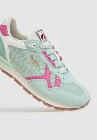 Sneaker verde menta con accenti rosa, materiali in camoscio e rete, punta tonda, chiusura con lacci e suola in gomma. Dettaglio del logo dorato sul lato.