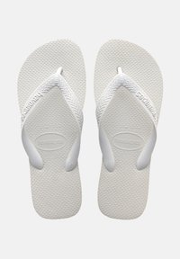 Witte rubberen slippers met textuur op de zolen en brede banden. Merkennaam "Havaianas" in de band geperst. Lichtgewicht ontwerp.