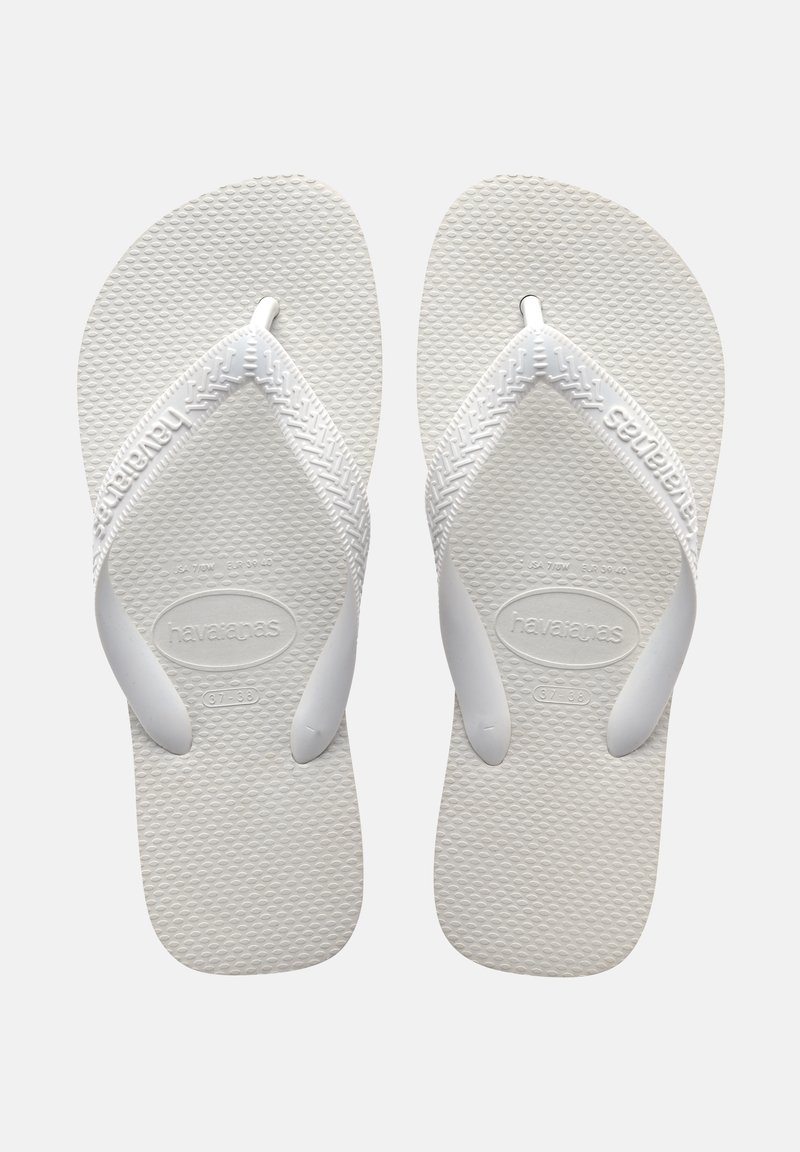 Witte rubberen slippers met textuur op de zolen en brede banden. Merkennaam "Havaianas" in de band geperst. Lichtgewicht ontwerp.