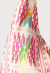 Χρωματιστή υφασμένη τσάντα με εκρού φόντο και πολύπλοκα σχέδια σε ροζ, πράσινο και πορτοκαλί, με έμφαση σε υφασμένη υφή.