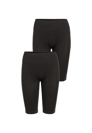 Witte mouwloze top met een ontspannen pasvorm, gecombineerd met zwarte biker shorts. Het model draagt zwarte sandalen; minimalistisch ontwerp, gladde textuur.