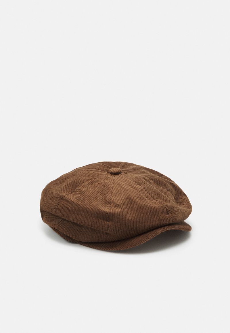 Casquette plate en velours côtelé marron avec une courte visière courbée et un petit bouton sur le dessus, présentée sur un fond blanc uni.