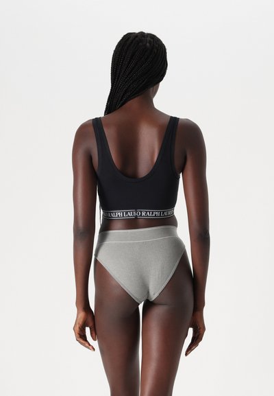 Svart racerback bralette med en kontrasterande logoband, kombinerad med ljusgrå ribbade höga trosor som visar en jämn textur.