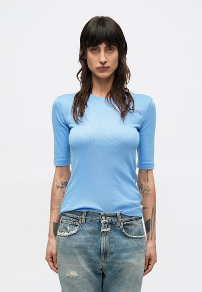 Light blue fitted t-shirt with short sleeves, made from a smooth fabric, paired with distressed light denim jeans.