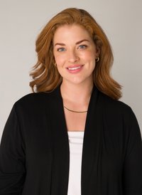 Zwarte cardigan met een losse pasvorm en lange mouwen, gedragen over een witte top. Het model draagt een eenvoudige gouden ketting en heeft golvend kastanjebruin haar.