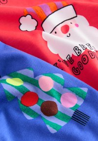 Tissu multicolore présentant un motif joyeux du Père Noël en rouge, blanc et violet, ainsi qu'un motif d'arbre bleu décoré d'ornements multicolores.