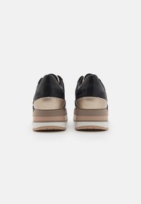 Sneaker neri con tomaia texture, accenti dorati lucidi e suola piatta beige stratificata. Presentano un collare imbottito per il comfort.