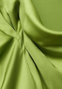 Tissu en satin de couleur vert lime vif, présentant de douces plis et une texture lisse. Le matériau reflète la lumière, mettant en valeur son éclat.