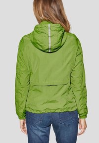Zielona nylonowa kurtka z kapturem, z odblaskowym paskiem z tyłu, elastycznymi mankietami i dołem oraz lekko luźnym krojem.
