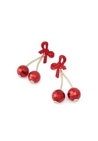 Wiszące kolczyki z czerwonymi kokardkami z cyrkoni oraz fasetowanymi czerwonymi koralikami w kształcie wiśni, zawieszonymi na złotych łodygach na białym tle.