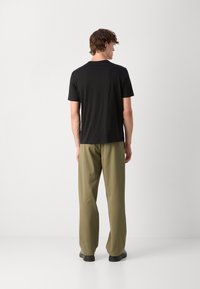 Black short-sleeve t-shirt paired with olive green wide-leg pants. Simple, clean design with a soft texture. No visible patterns or accents.