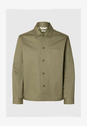 Olivzaļš garām piedurknēm krekls ar smailu apkakli, priekšējām pogām un krūšu kabatu uz vienveidīga gaiša fona.