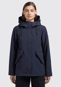 Giacca impermeabile blu navy con colletto alto, cappuccio regolabile e tasche frontali. Texture liscia con design minimalista e dettagli del logo discreti.