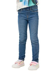 Niebieskie dżinsy skinny z gładką teksturą i klasycznym pięciopocketowym fasonem. W zestawieniu z pastelowymi sneakersami z rzepami.